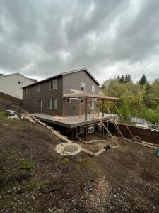 Brown house with partially completed deck and patio cover on two sides.