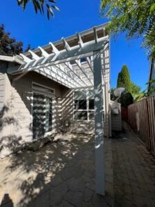 White pergola over a stone patio.